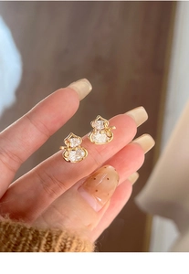 Detail of gold-plated gourd stud earrings with paved zircons and bow accents