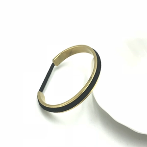 Detailed view of C-shaped rose gold bracelet featuring an integrated black elastic hair tie