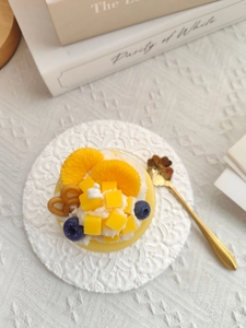 Top view of a dessert scented candle with fruit toppings on a decorative white lace plate