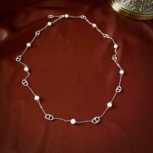 Detailed view of long pearl necklace with pig nose links on dark red silk background
