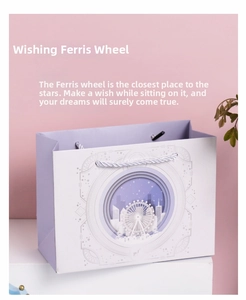 Detail einer lila Geschenktüte aus Papier mit 3D-Riesenrad-Design und Kordelgriffen