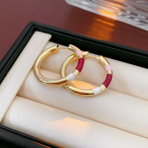 Macro shot of geometric gold earrings with colorful enamel in an jewelry gift box