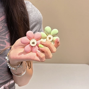 Close-up of pink and green floral phone grips with resin petals and golden heart centers