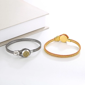 Detail view of creative zipper-shaped bangles in silver and gold-red on a minimalist book
