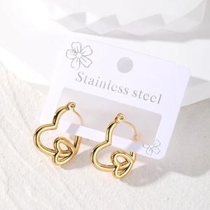 Polished golden stainless steel double heart hoop earrings on a minimalist white display