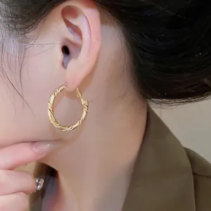 Fashionable golden twisted geometric hoop earrings for women in a stylish minimalist design
