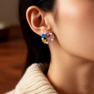 Detail of a floral wreath earring with colorful heart gems and pearls on model