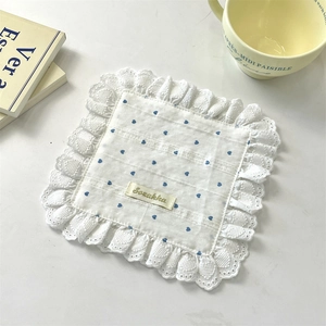 Detail view of square lace placemat featuring blue heart prints and embroidered logo
