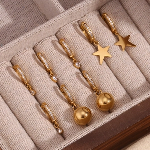 Macro detail of 18K gold plated hoop earrings with star and heart zircon pendants