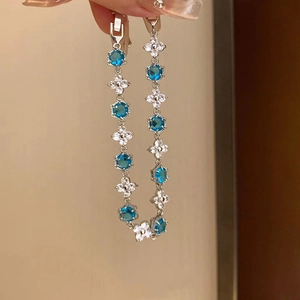 Silver flower and hexagonal blue zircon bracelet held by hand for a stylish jewelry display