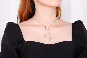 Detail of silver Y-shaped tassel necklace with heart connector and vintage portrait charms
