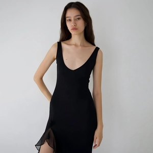 Détail d'une robe noire sans manches avec décolleté en V et fente ornée de volants
