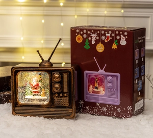 Close-up of retro TV music box with glowing Santa scene and Christmas gift box