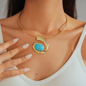Close-up of golden spiral torque necklace with a green oval turquoise stone on a model