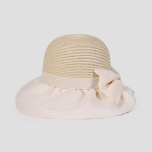 Dettaglio dell'elegante cappello da sole beige con tesa larga e grande fiocco per l'estate