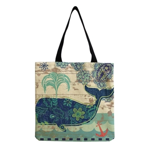 Canvas tote bag with blue whale paisley print and black handles on beige background