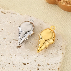 Detail view of gold and silver hollow ice cream cone pendants on textured stone background