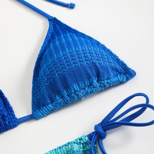Primo piano del top bikini blu con motivo a spina di pesce e dettagli con lacci