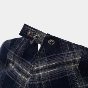 Detail of navy plaid cap showing silver metal snap buttons and thick fabric texture