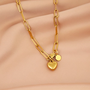 Detail of a gold heart pendant on a stylish paperclip chain over silk fabric