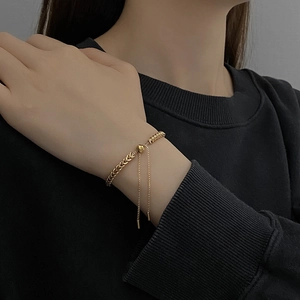Adjustable gold titanium steel wheat woven bracelet on a model with a black sweater