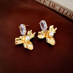 Macro detail of vintage gold plated earrings featuring clear zircon and white pearl accents