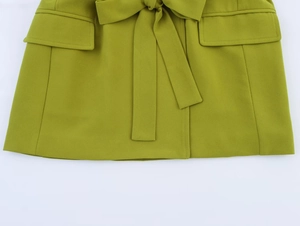 Detail of olive green blazer waist with drawstring bow and large flap pockets