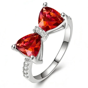 Luxurious bow-shaped ring with red triangle zircons and silver metal band on white base