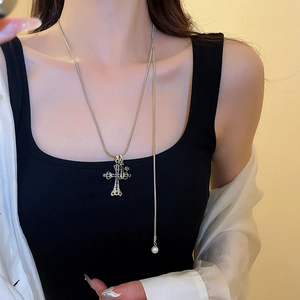 Dettaglio della collana con ciondolo a croce di diamanti e perla finale