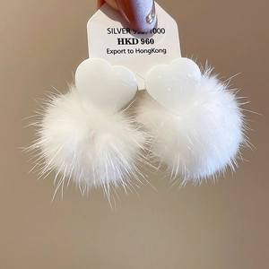 Detail showing white heart-shaped studs with plush pom-poms on S925 silver needles