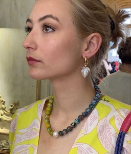 Detail shot of blue heart glass earrings and beaded pearl necklace worn by a female model
