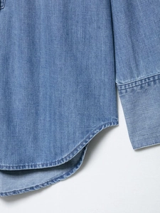 Detail of curved hem and stitching on light blue denim shirt for women fashion
