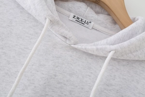Detail shot of grey hooded sweatshirt neckline with drawstring and brand label