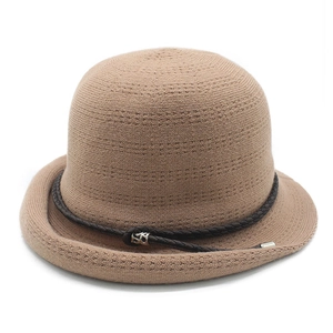 Detailed knit texture of a camel cloche hat with a brown braided leather band