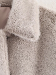 Detailed close-up of soft light grey faux fur texture on the collar of a plush jacket