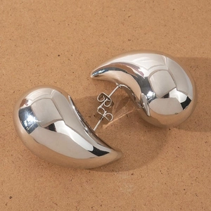 Detail view of large silver teardrop earrings with a high-polished mirror finish