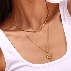 Detail of layered 18K gold plated necklace with sunburst pendant and green stone