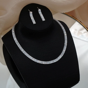 Detailed close-up of a silver zircon necklace and earrings set on a black display stand