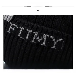 Nahaufnahme der schwarzen Strickmütze mit weißer FLTY-Stickerei und feiner Rippenstruktur