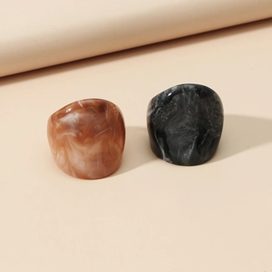 Detail view of two acrylic rings with marble texture in brown and black resin