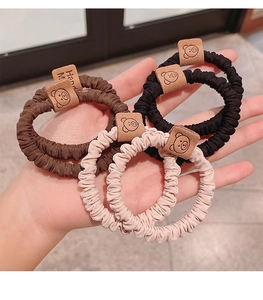 Detail showing elastic hair ties in black, brown, and beige with cute bear felt tags