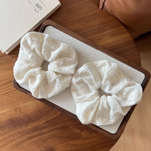 Macro shot of white lace embroidered hair scrunchies on a wooden tray set