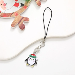 Detail of penguin charm phone strap with green and red enamel hat on white background