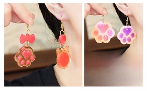 Detailed view of DIY resin cat paw earrings with glitter and red bow accents