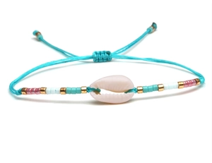 Detail of bohemian woven bracelet featuring a natural shell and turquoise beads on blue cord