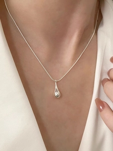 Close-up of minimalist S925 sterling silver teardrop pendant on a sleek snake chain