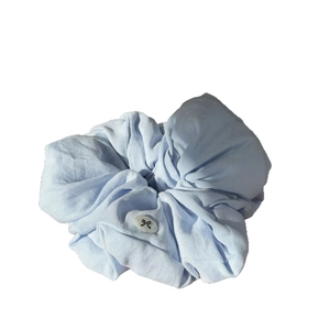 Light blue cream puff hair scrunchie with cute black bow button detail on white background