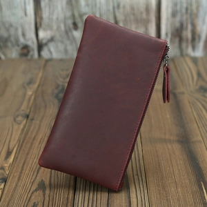 Vue détaillée du portefeuille en cuir crazy horse brun rouge avec fermeture éclair sur bois