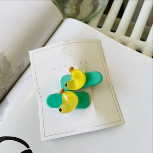 Détail de barrettes vert menthe mat avec décorations en résine jaune sur carte blanche