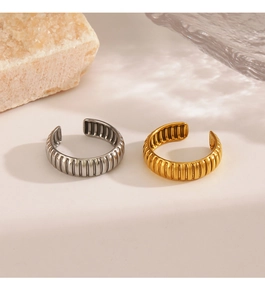 Close-up of gold and silver ribbed open rings on a minimalist stone background
